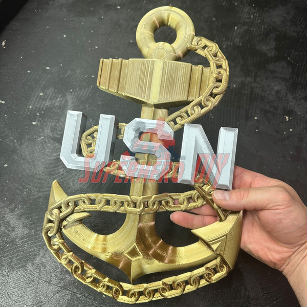 Gold navy anchor with chain and silver letters spelling USN held in hand against dark background. - SuperheroDIY