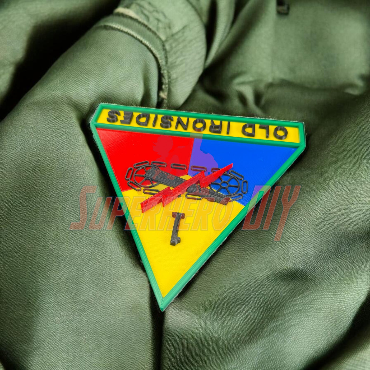 1st Armored Division display insignia featuring Old Ironsides patch on green fabric background.