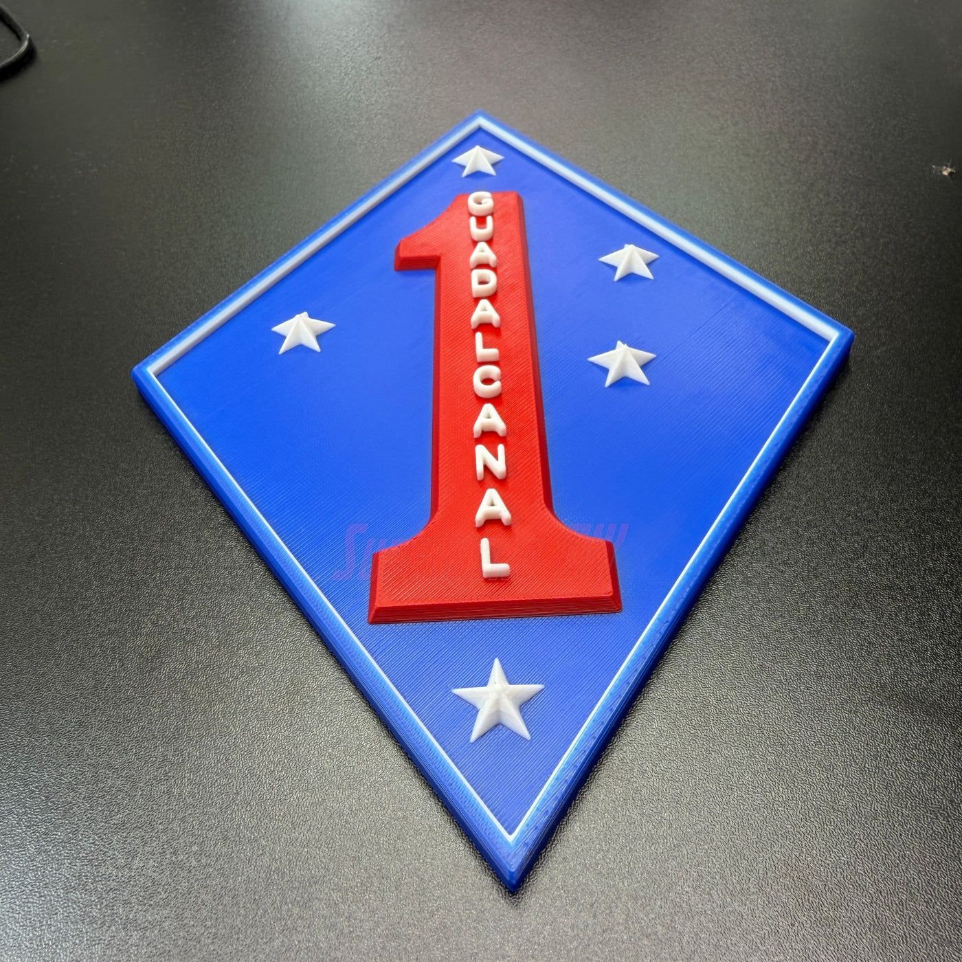 1st Marine Division display insignia featuring blue diamond, red numeral one, and stars, representing Guadalcanal