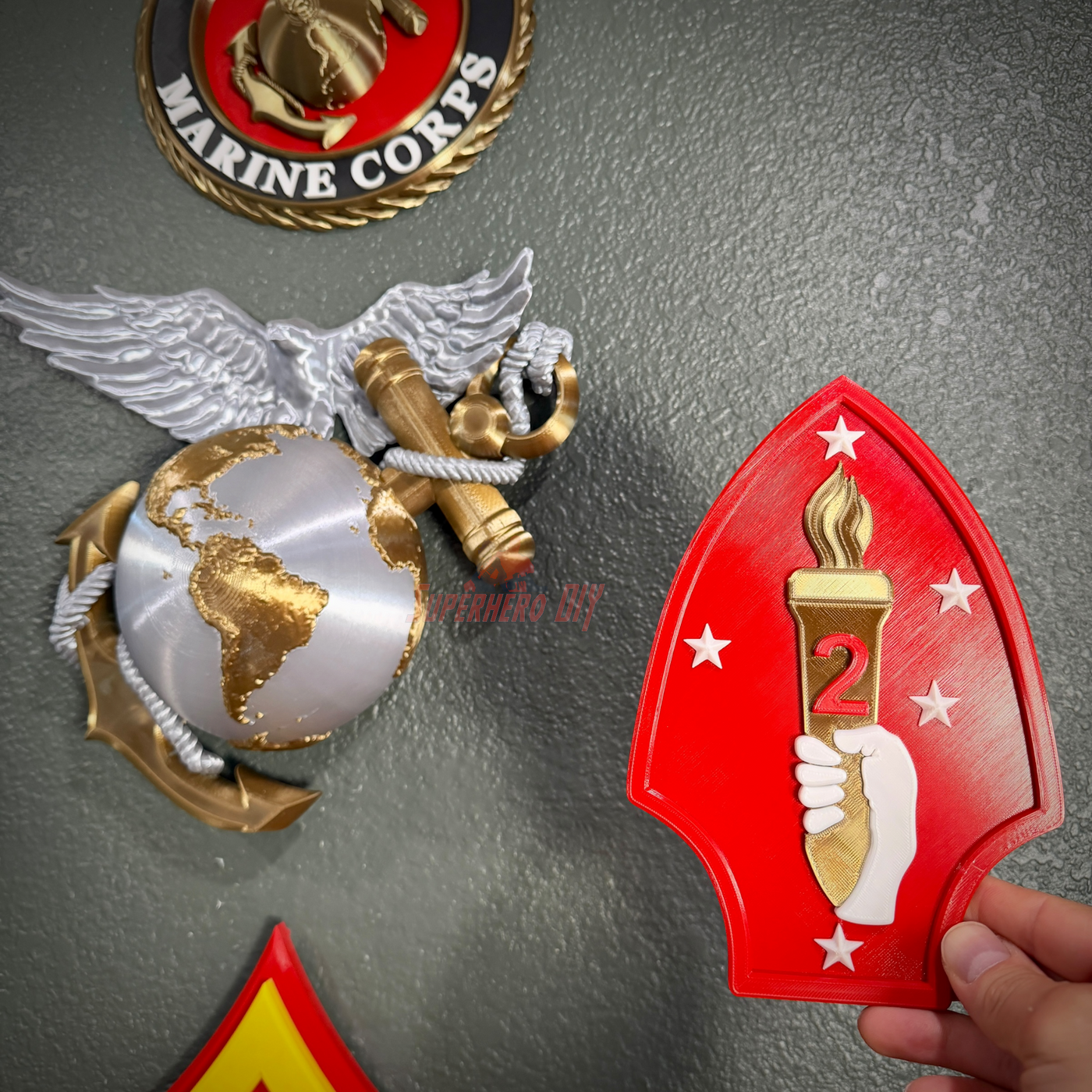 2nd Marine Division display insignia held next to Marine Corps emblem, showcasing vibrant colors and detailed design.