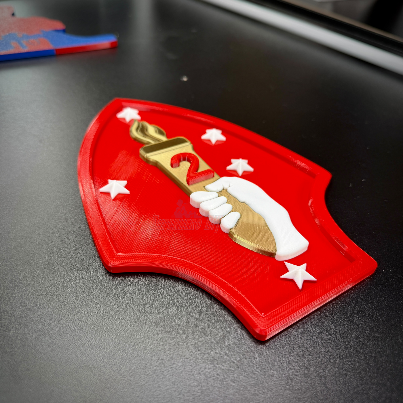 2nd Marine Division display insignia featuring a red background, gold torch, and white hand, perfect for wall or case display.