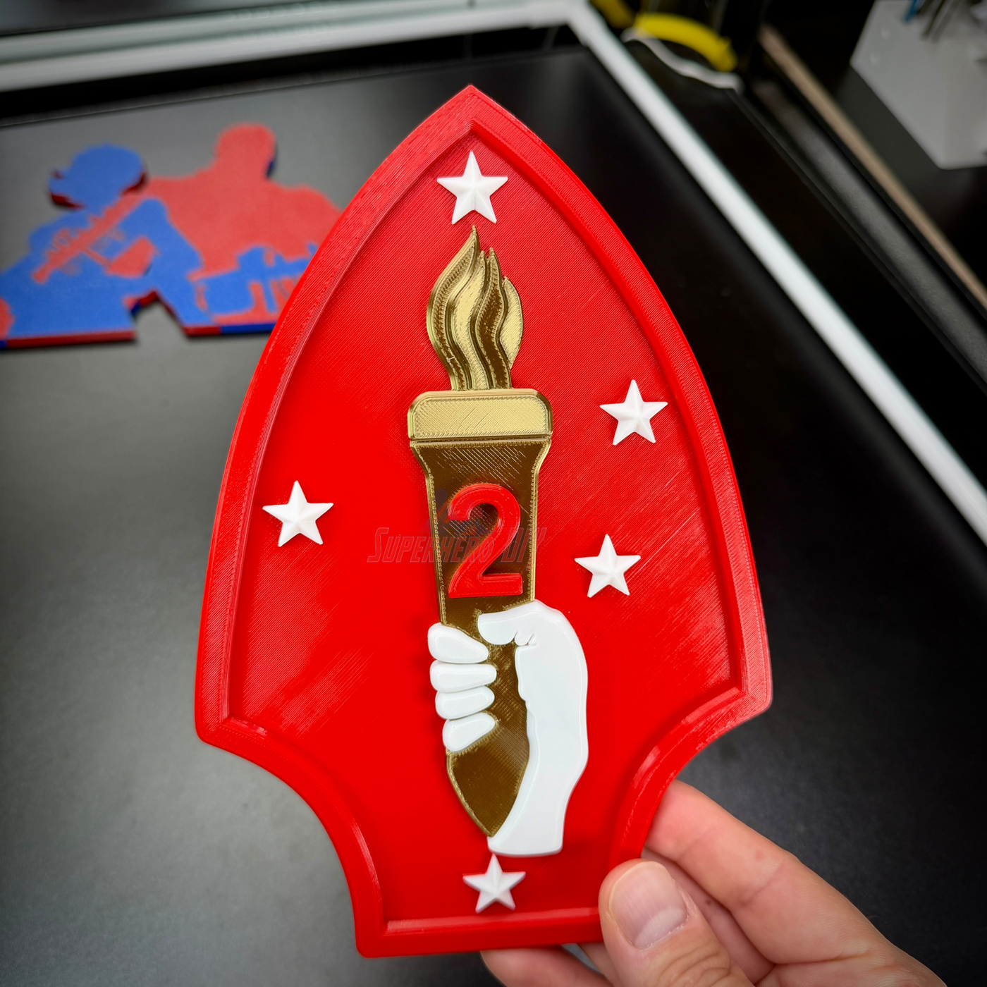 2nd Marine Division display insignia featuring a red shield with a torch and stars, representing the 2nd Marines.