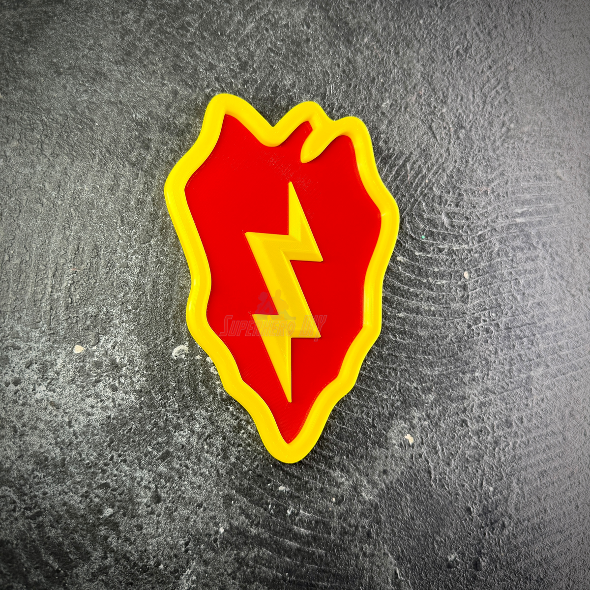 Front view of the 25th Infantry Division taro leaf display insignia lying flat on a dark stone surface