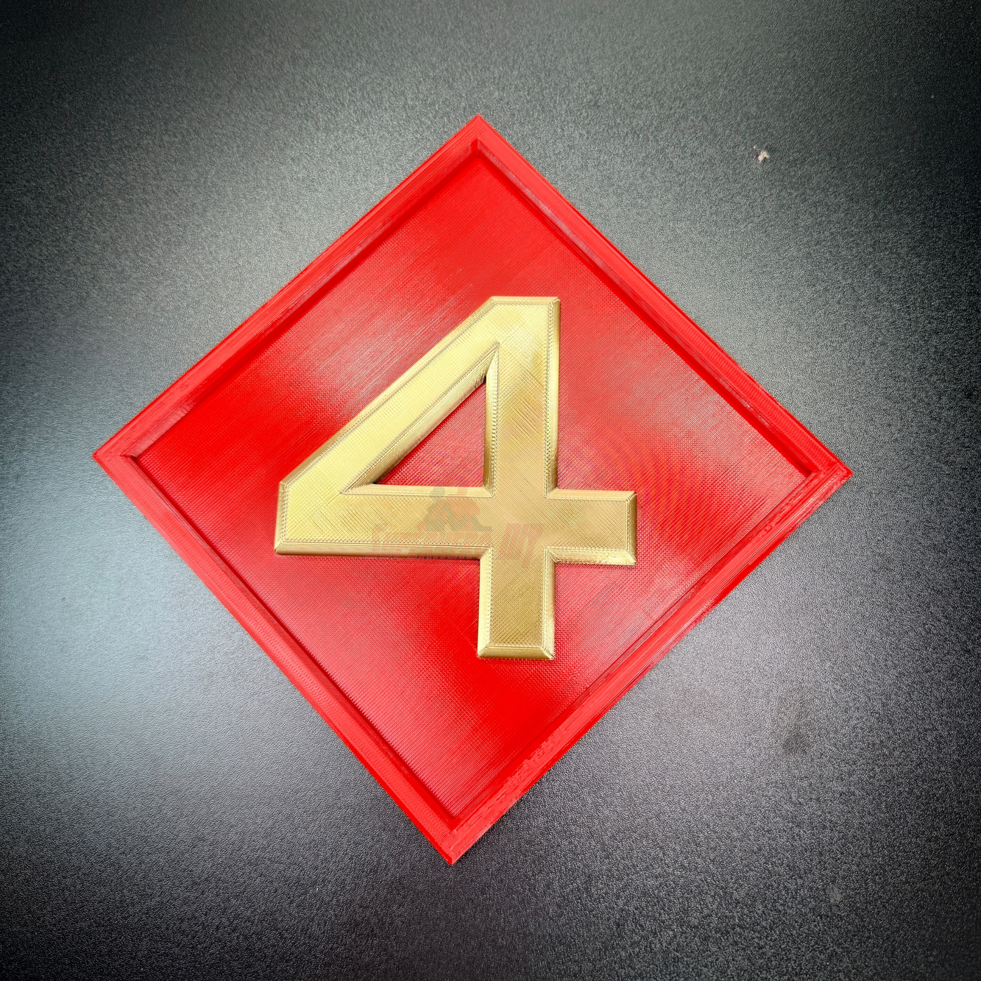 4th Marine Division insignia in relief, featuring a gold numeral 4 on a red diamond background.