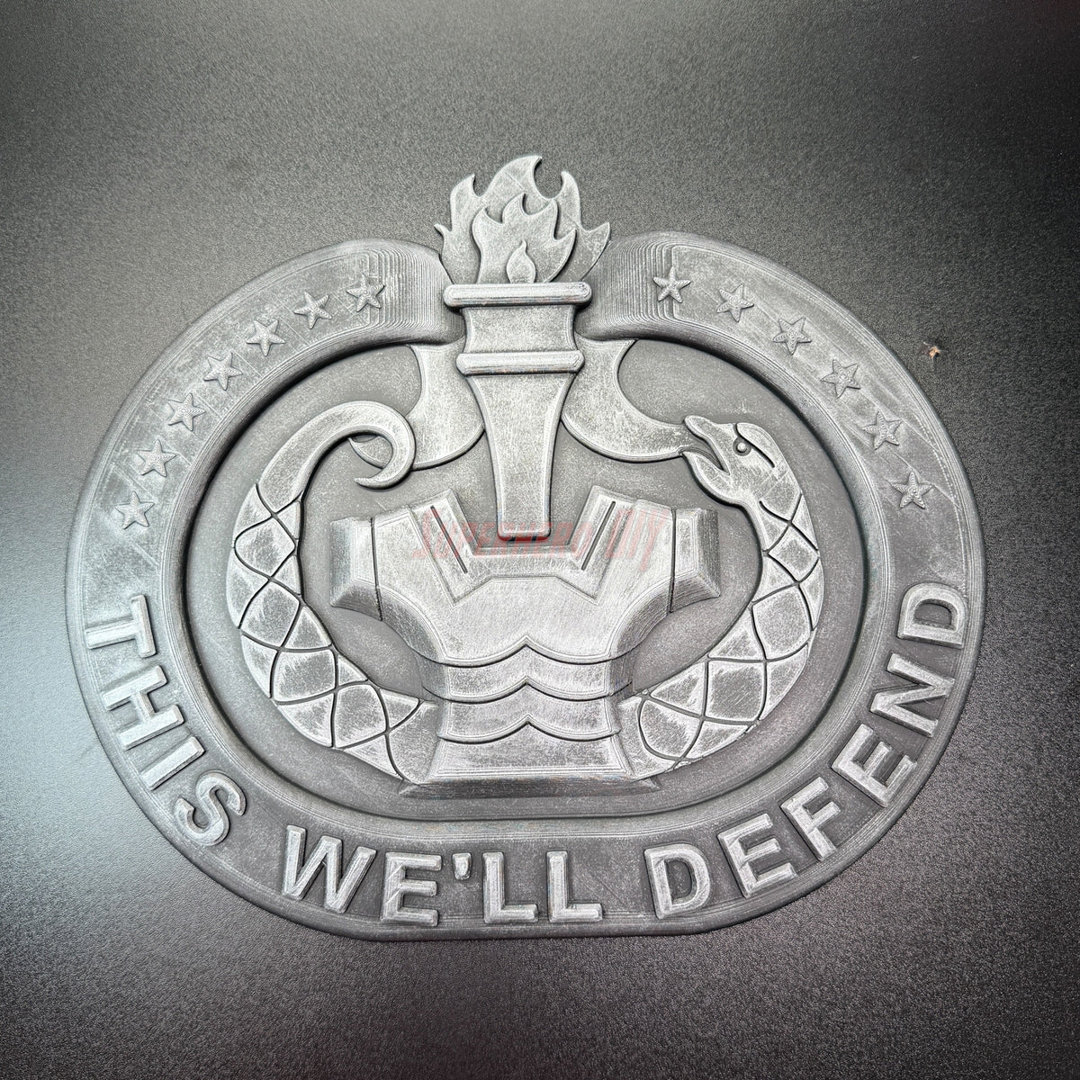 3D US Army emblem featuring a torch and snake with the text 'THIS WE'LL DEFEND' for patriotic displays.