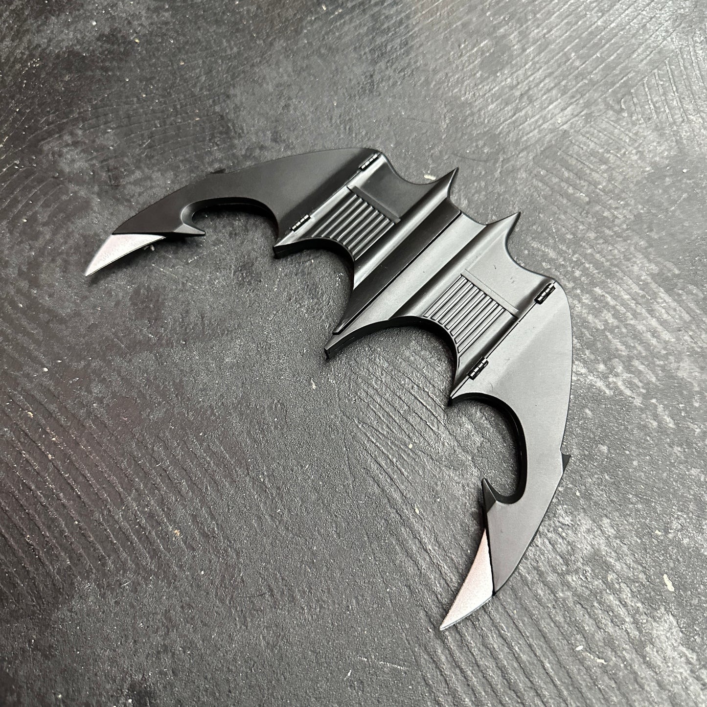 NECA BATMAN 1989 Folding Magnetic Batarang (LOOSE) displayed on a black surface, showcasing its sleek design.