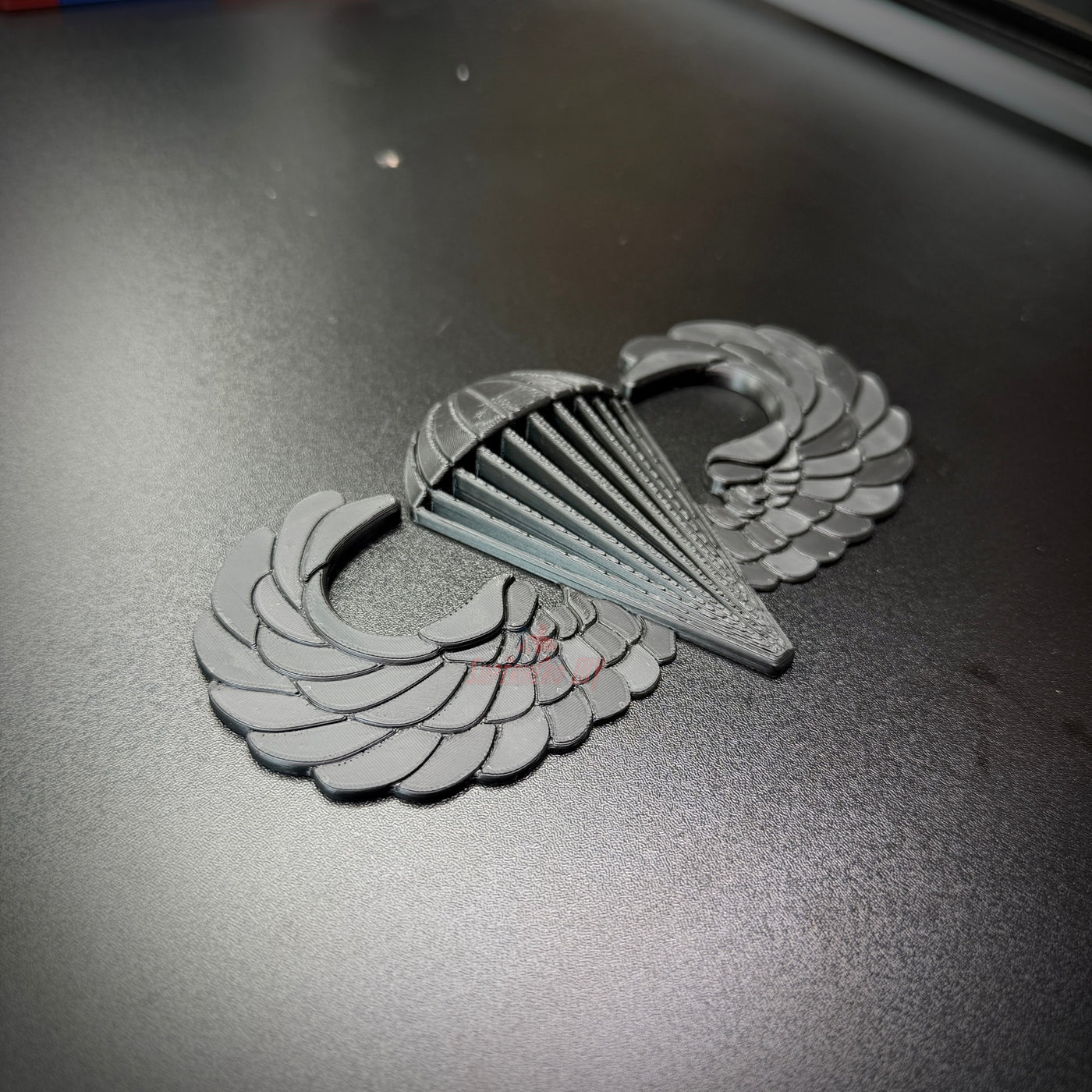 Image of a replica airborne jump wings badge featuring intricate wing and parachute designs.