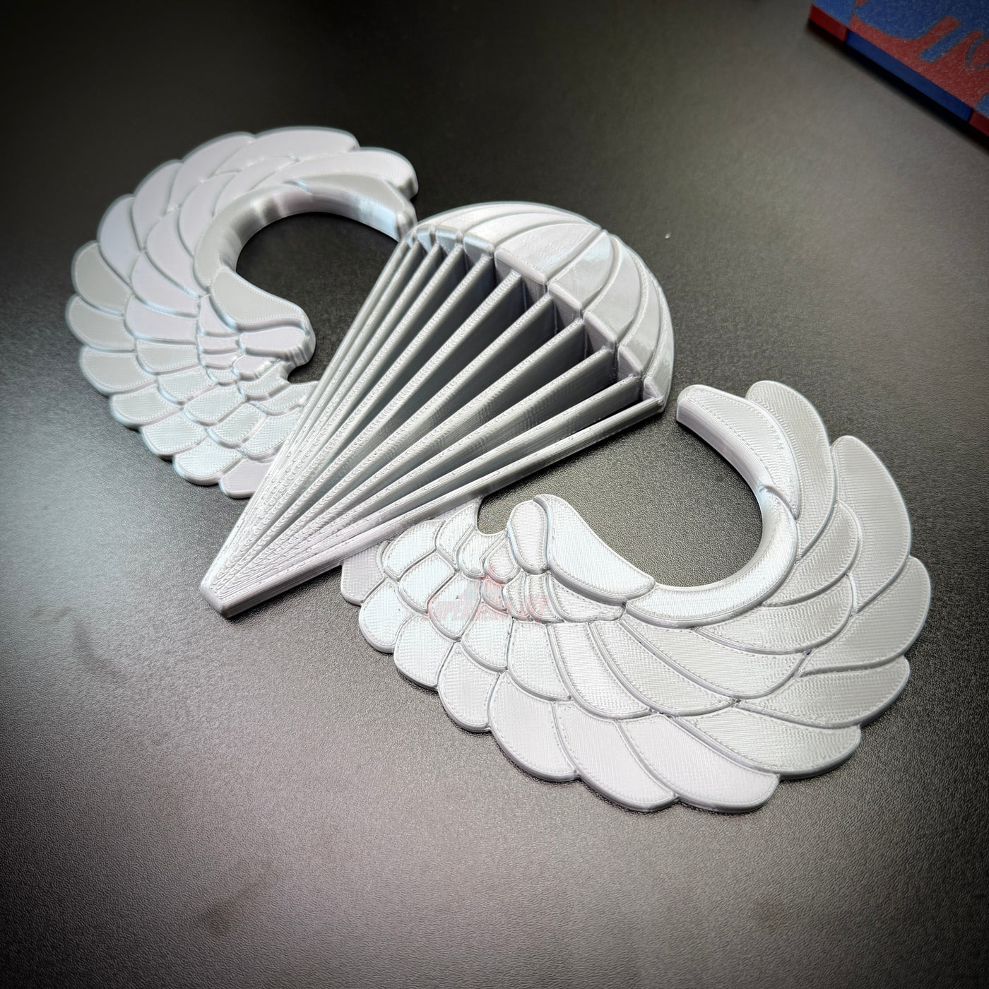 airborne jump wings badge replica displayed on a dark surface, showcasing its detailed design and craftsmanship.