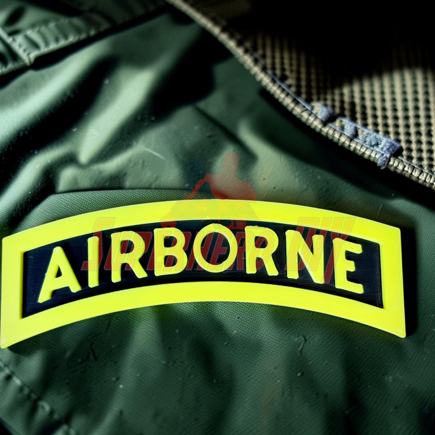3D airborne tab displayed on fabric background with bold yellow lettering and black border
