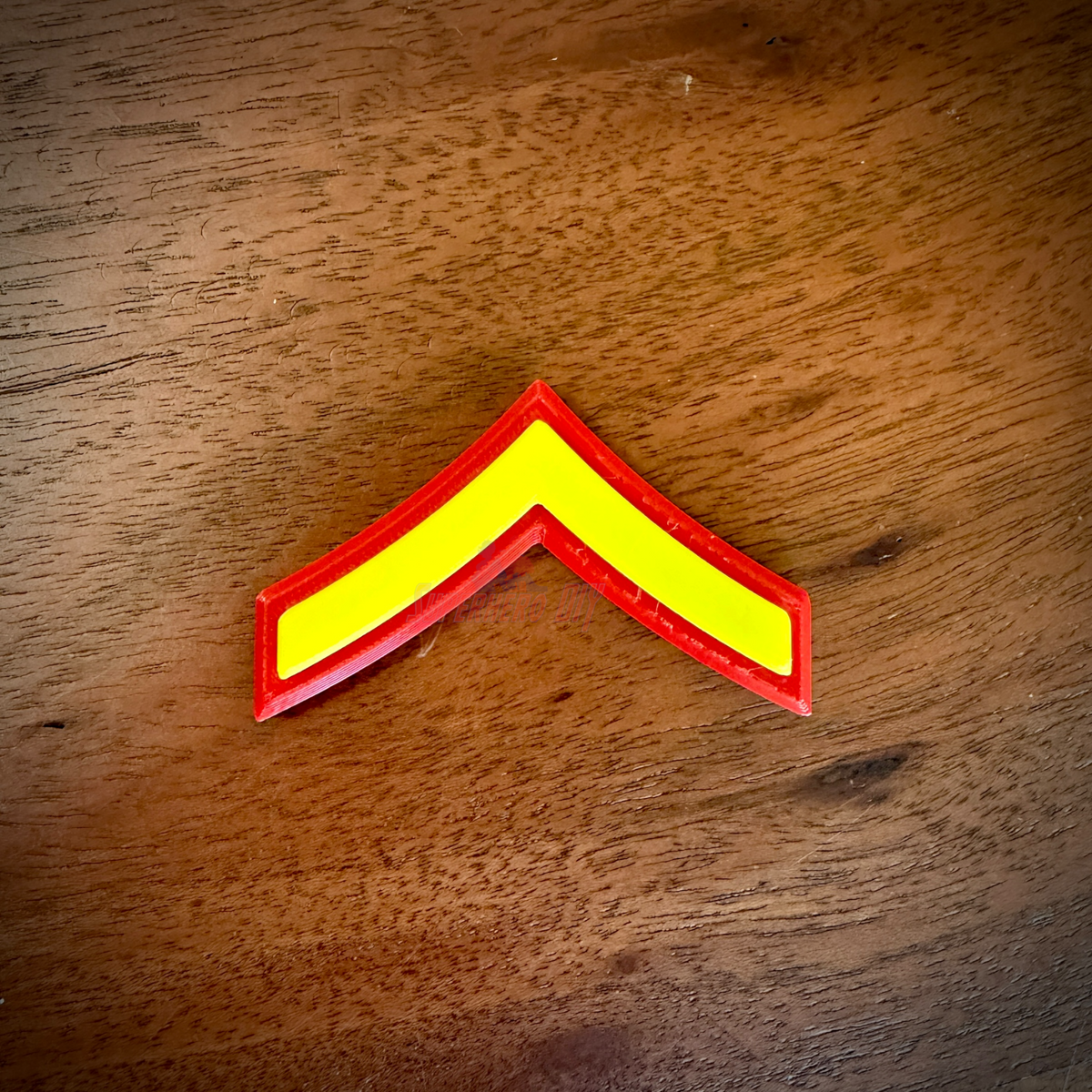 USMC Private First Class (E-2) single chevron rank insignia lying on a wood surface