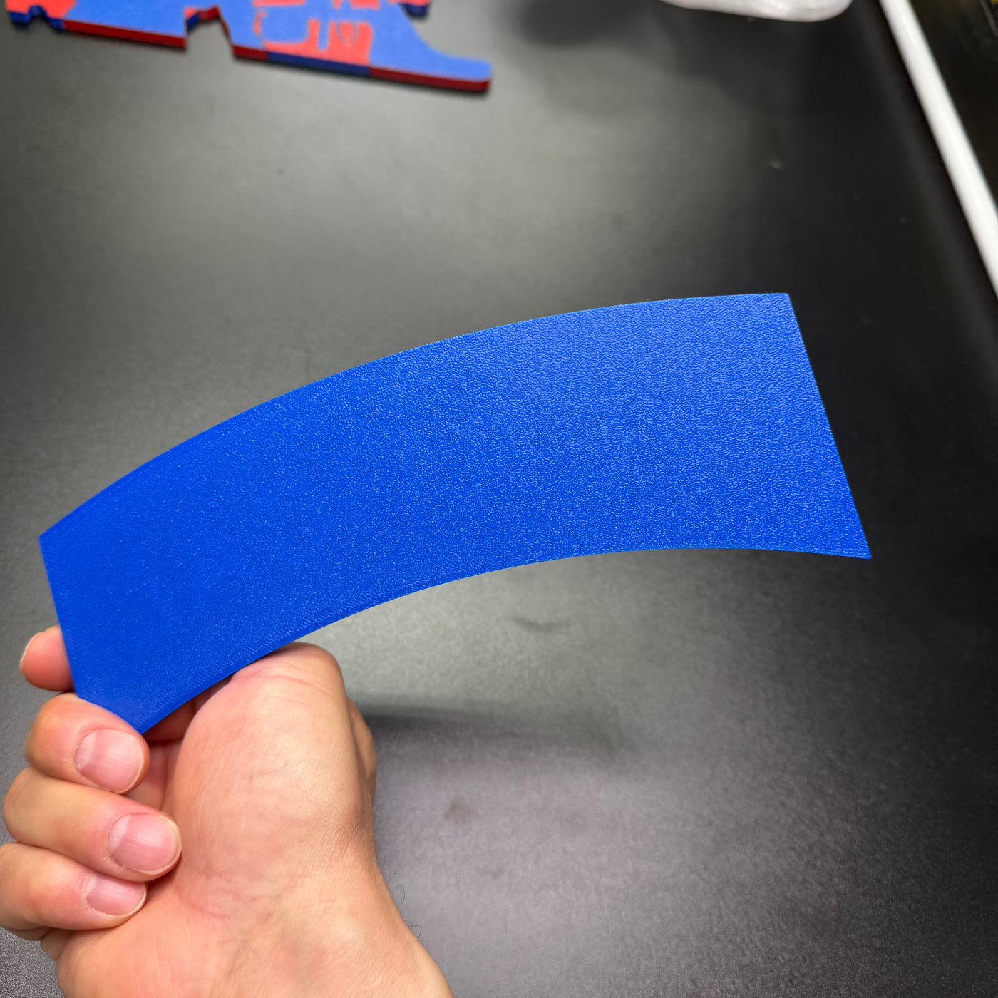 3D vertical construction engineer tab in blue held in hand, showcasing its curved design and texture.