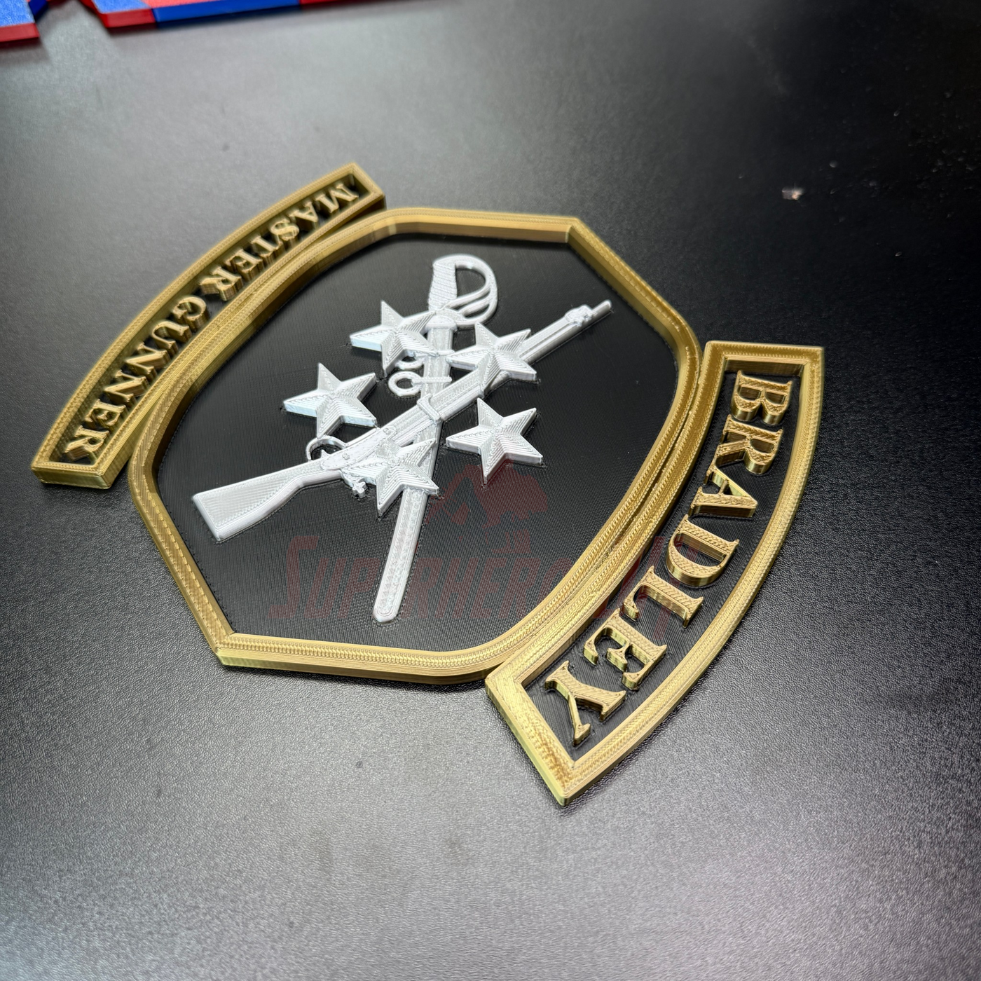 Bradley Master Gunner Badge display showing the insignia with crossed weapons and stars in a detailed design.