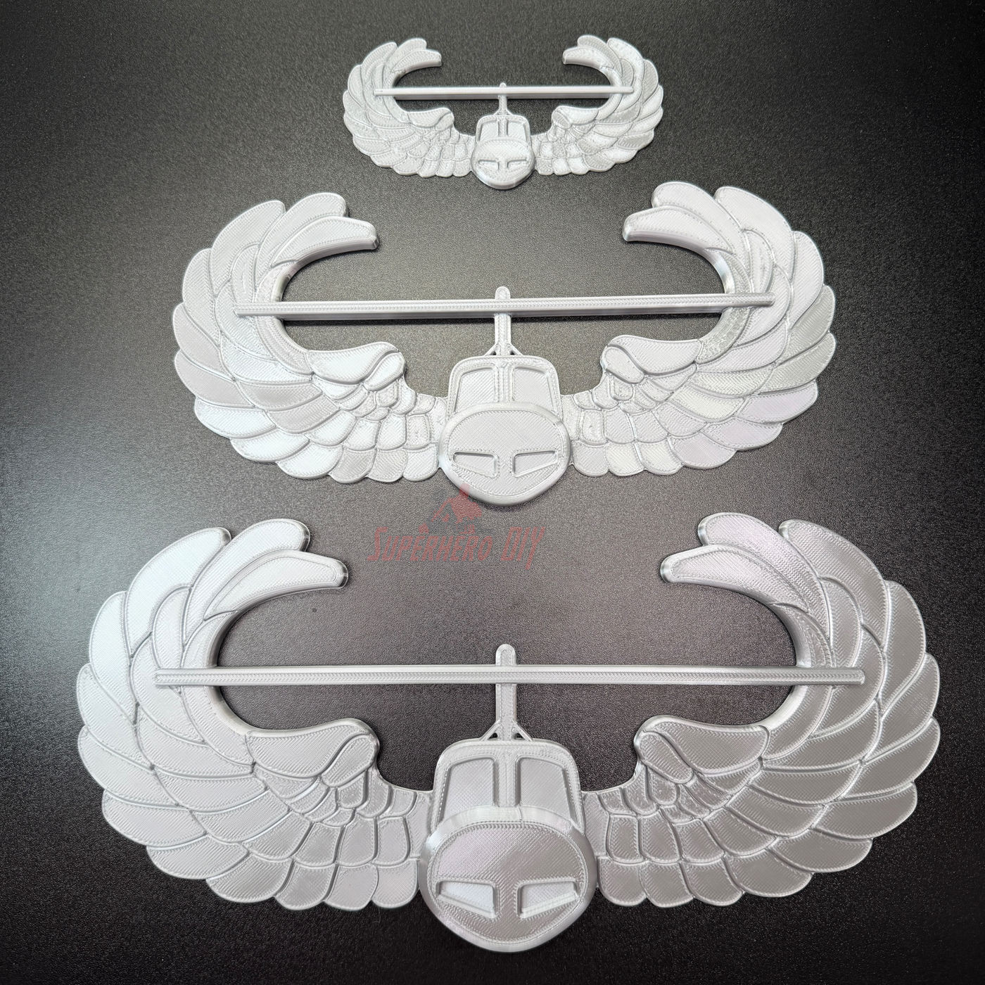 Air Assault Badge display featuring multiple wings in shiny silver finish on a black background.