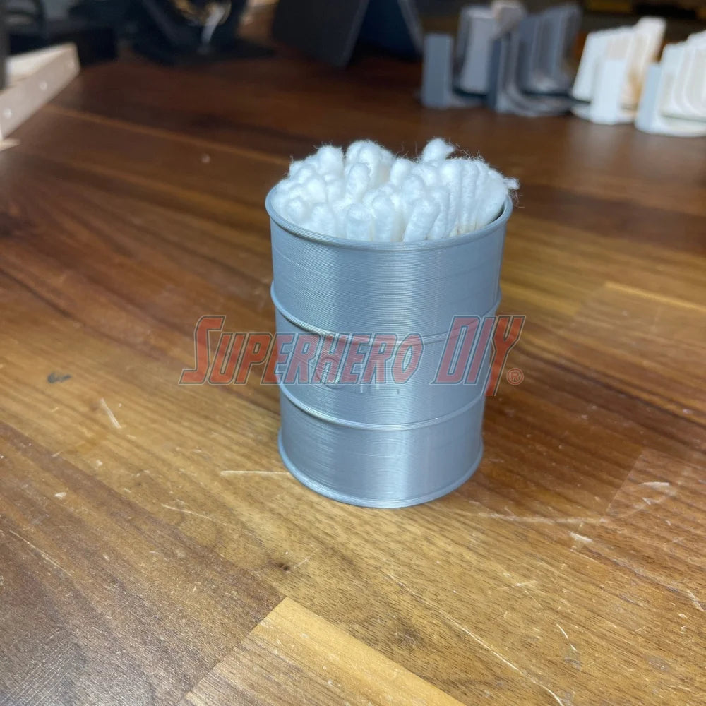 3D-printed mini oil drum desk organizer filled with q-tips, shown on a wooden surface.