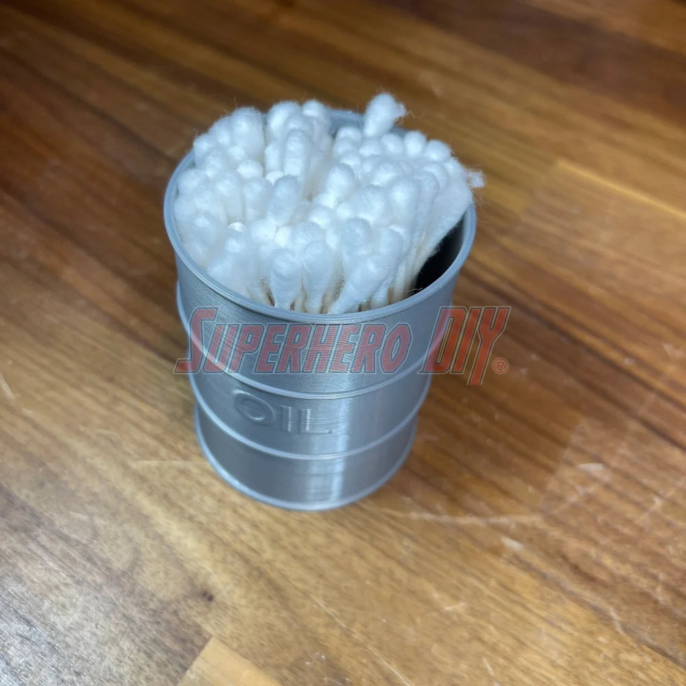 Mini oil drum desk organizer holding cotton swabs on a wooden surface