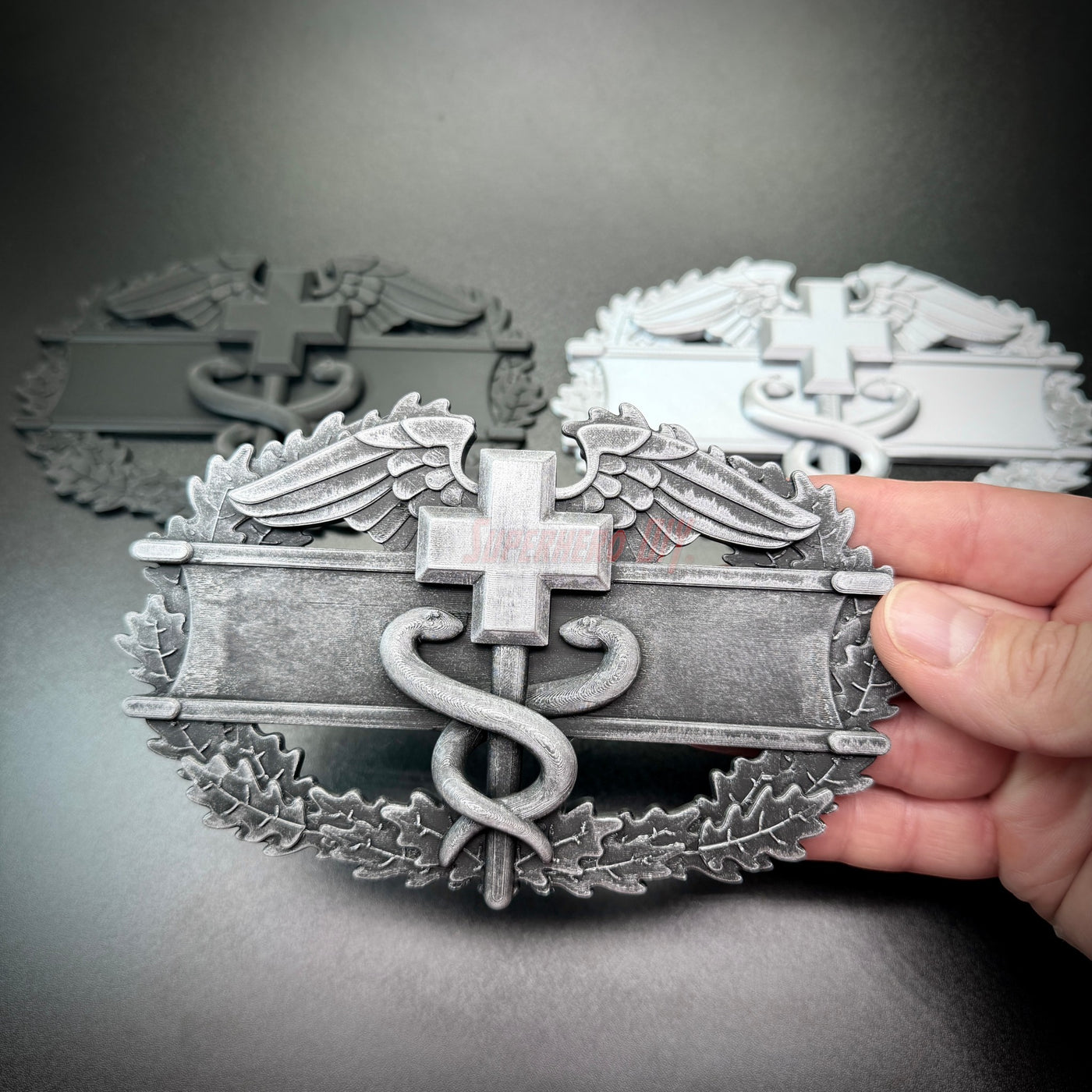 Army medical badge display featuring EFMB, CMB, MCMB badges on a decorative wall piece.