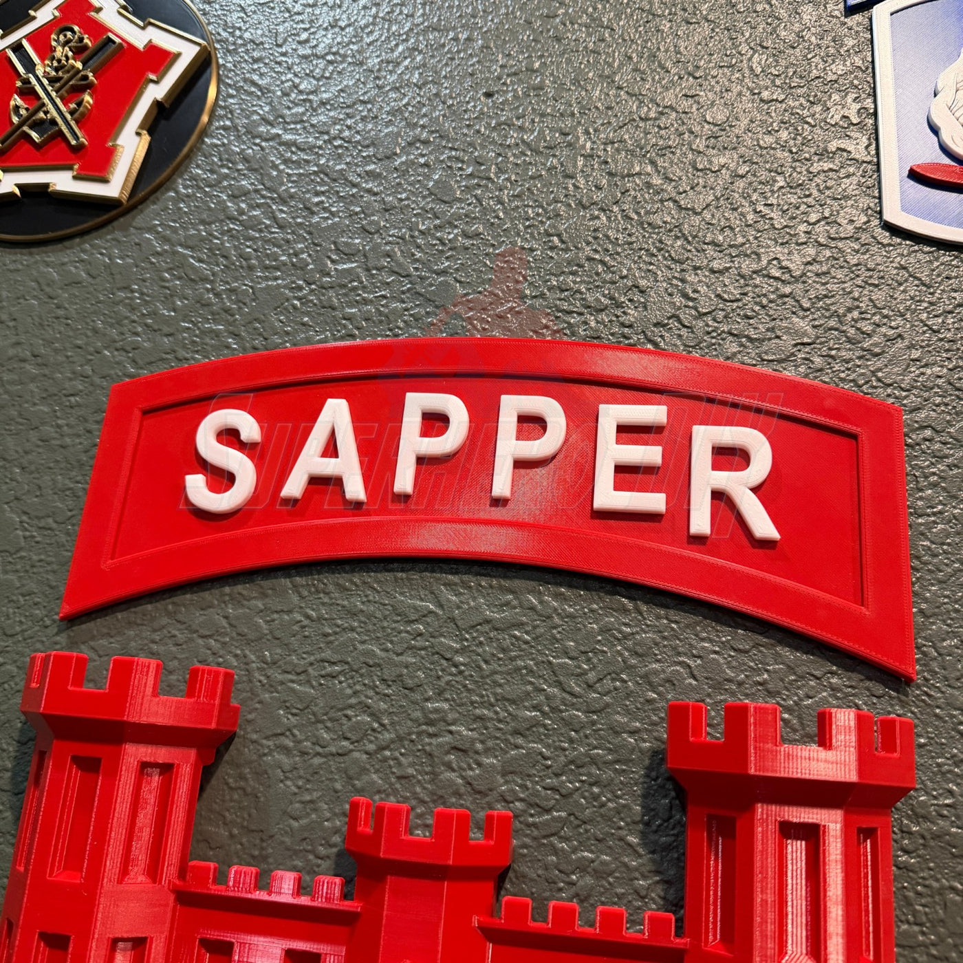 3D sapper tab display piece in red with the word 'SAPPER' prominently featured.