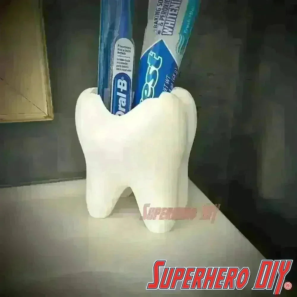 Tooth shaped bathroom organizer holding toothpaste and toothbrush on a sink.