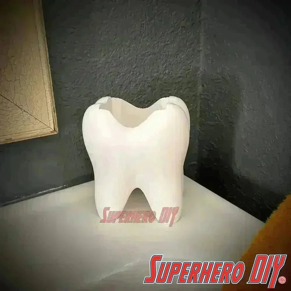 Tooth shaped bathroom organizer on a countertop, ideal for holding toothbrushes and toothpaste. Functional and stylish bathroom accessory.