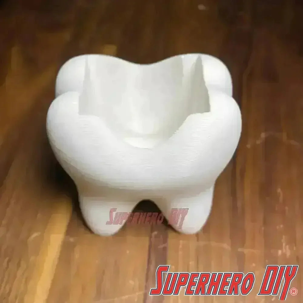 Tooth shaped bathroom organizer for toothbrush and toothpaste storage on wooden surface.