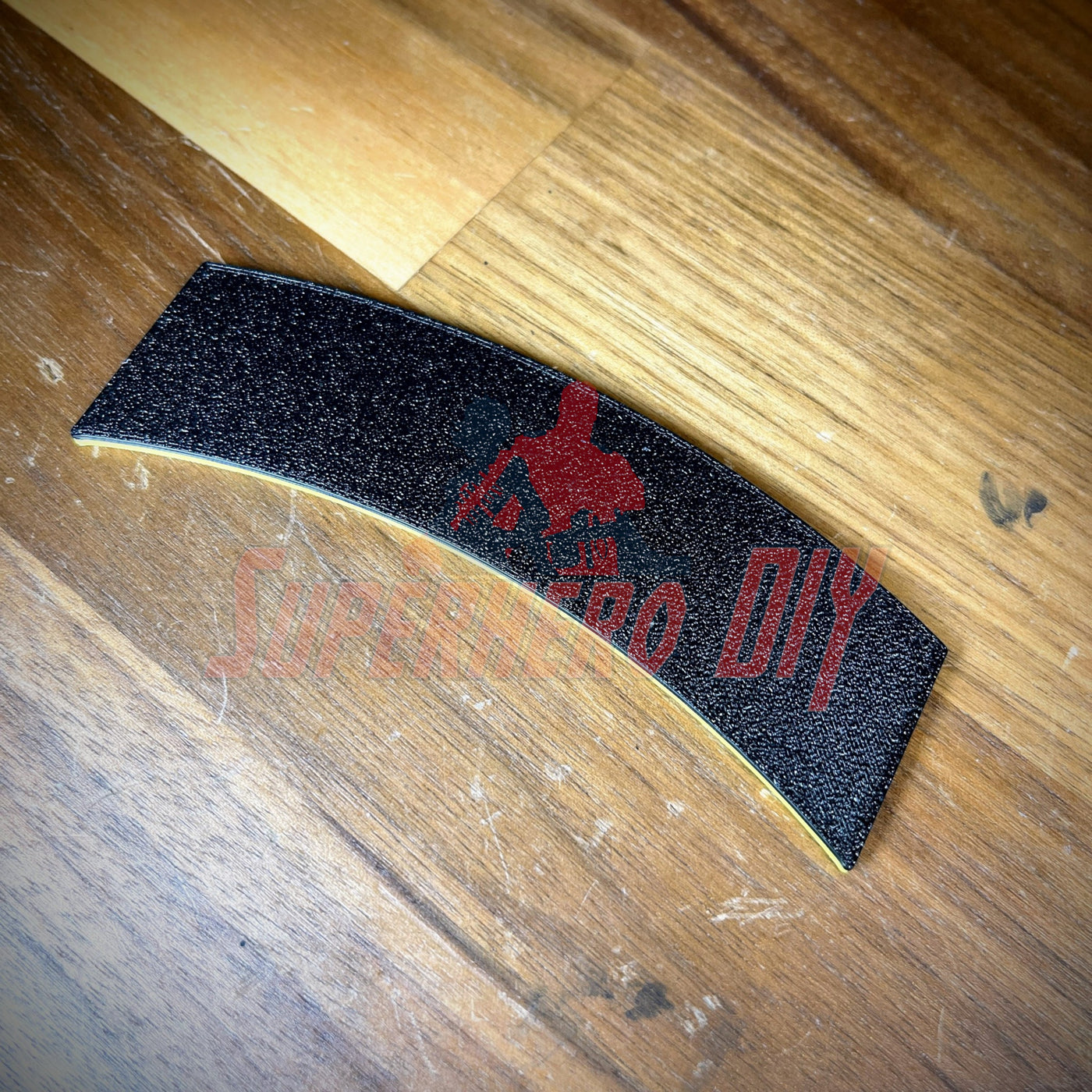 3D airborne tab displayed on a wooden surface, featuring a solid black design with yellow accents.