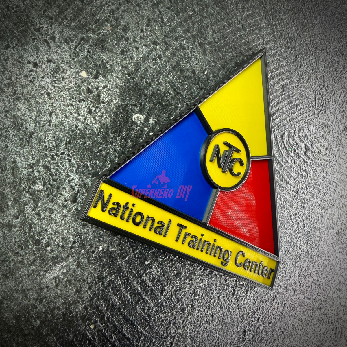 National Training Center insignia display tilted on gray concrete, raised NTC monogram in the center ring