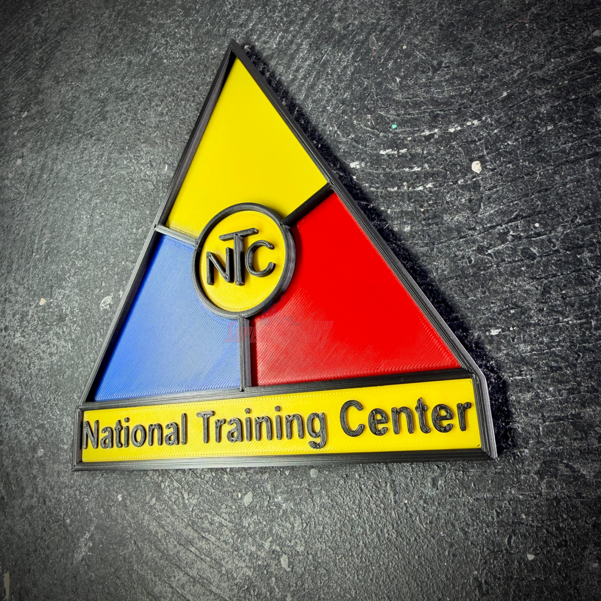 Angled close view of the National Training Center display insignia, blue and red panels around the NTC ring