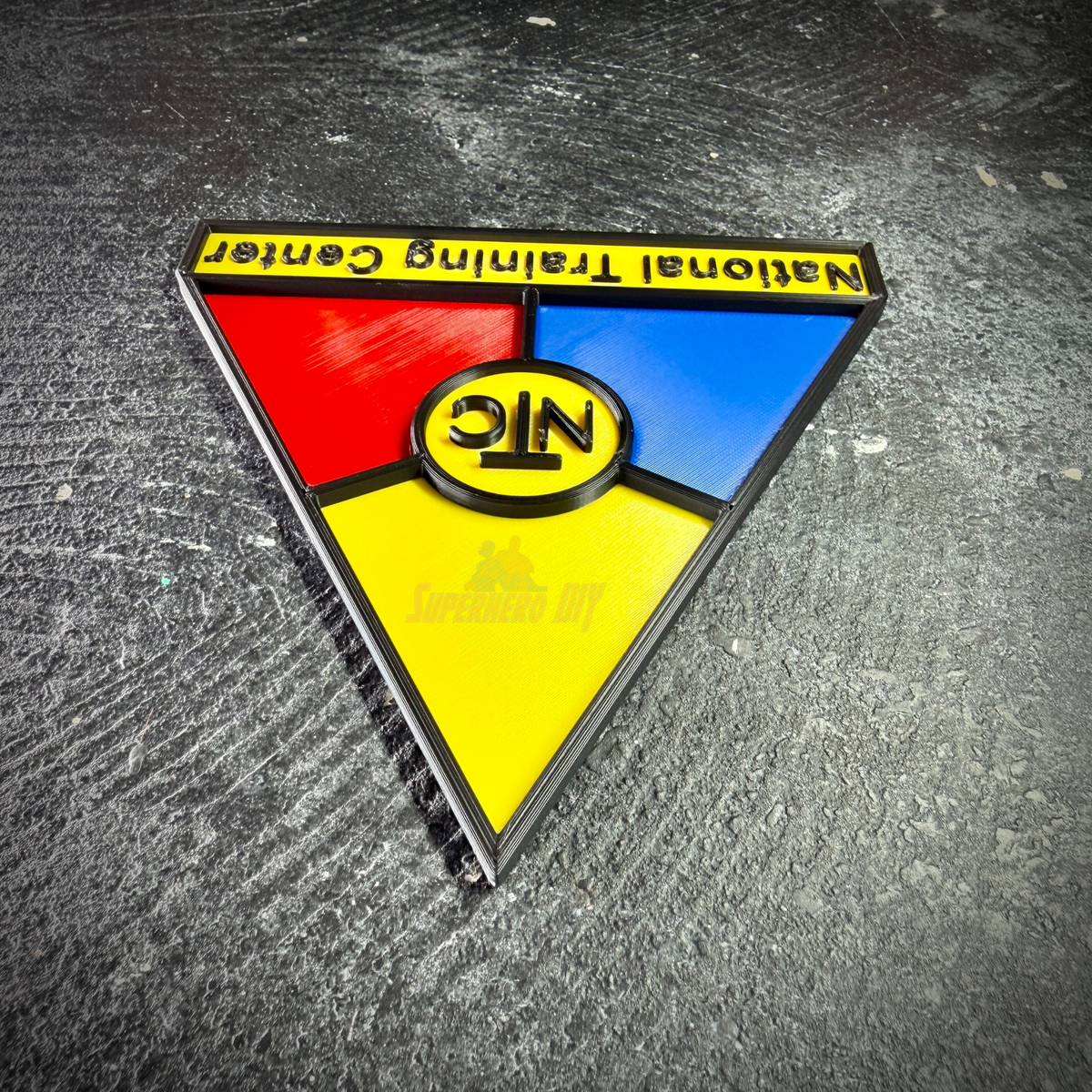 NTC wall display insignia upside down on concrete, showing the raised edges on every color panel