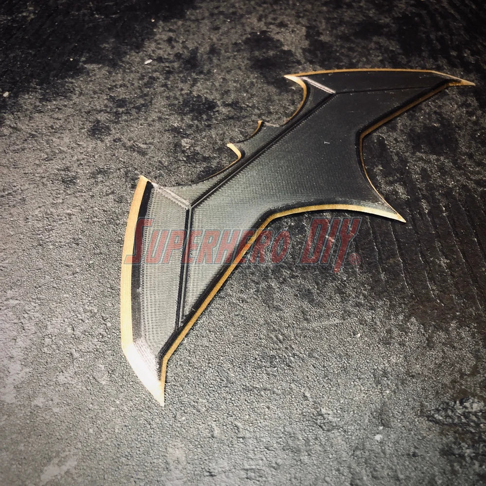 3D-printed plastic BvS JL batarang prop in black and gold, perfect for cosplay and costume accessories.