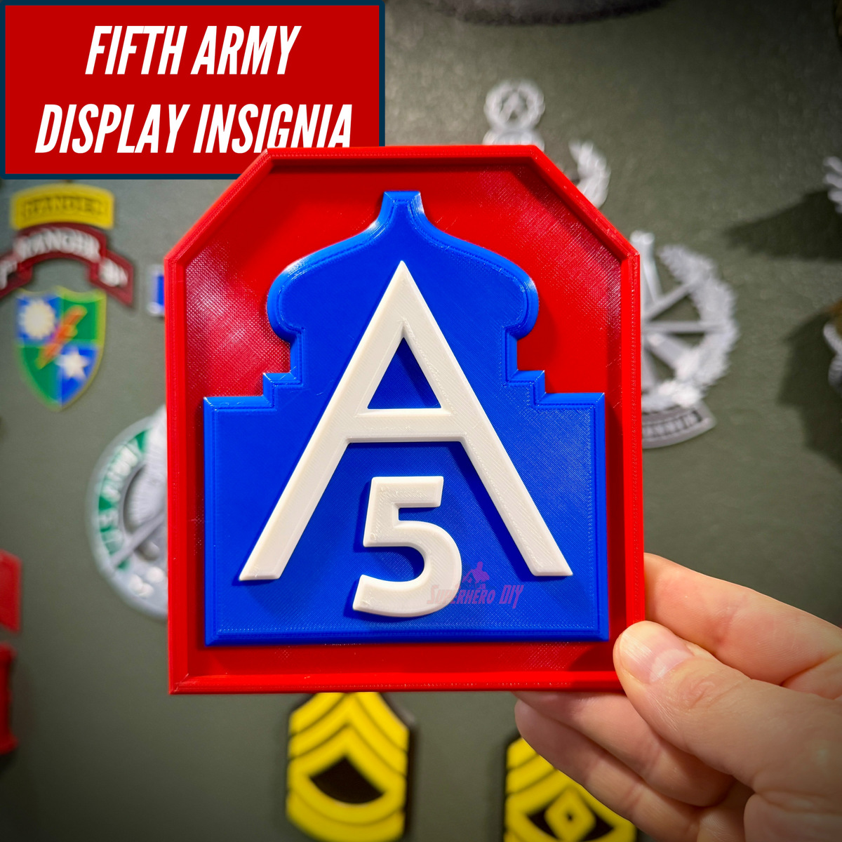 Hand holding the Fifth Army display insignia in front of a wall of other military badge and rank displays