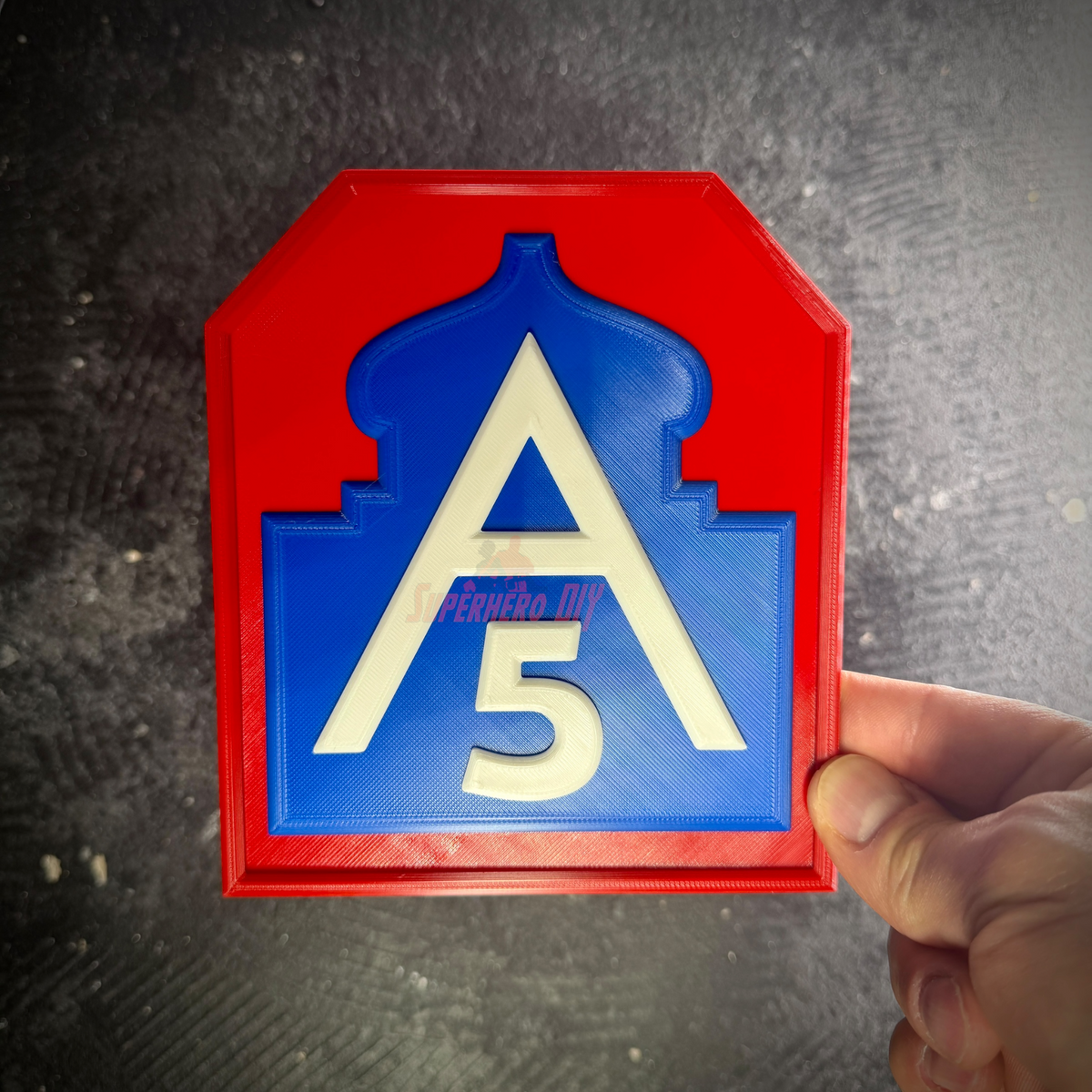 Fifth Army shoulder sleeve insignia display held by hand against a gray background, front view