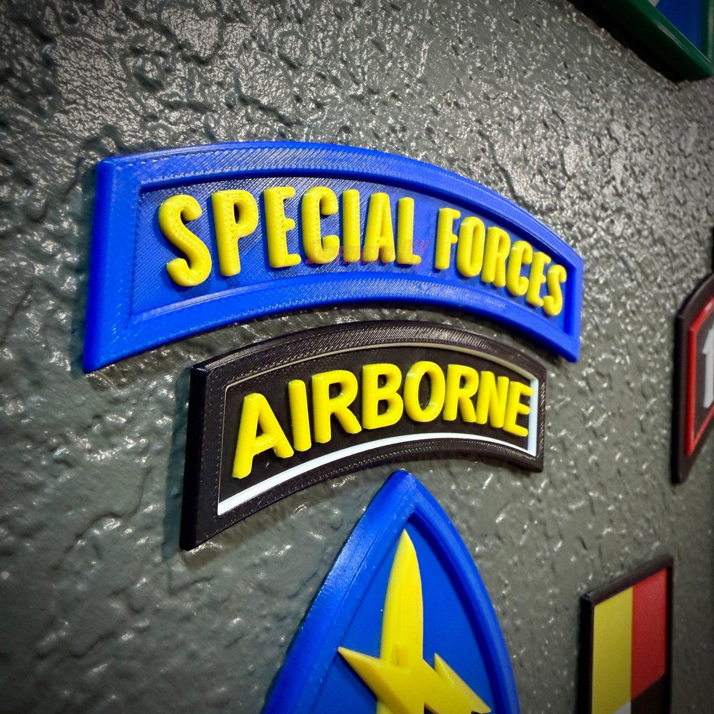 Special Forces display insignia featuring Special Forces and Airborne tabs on a textured wall background.