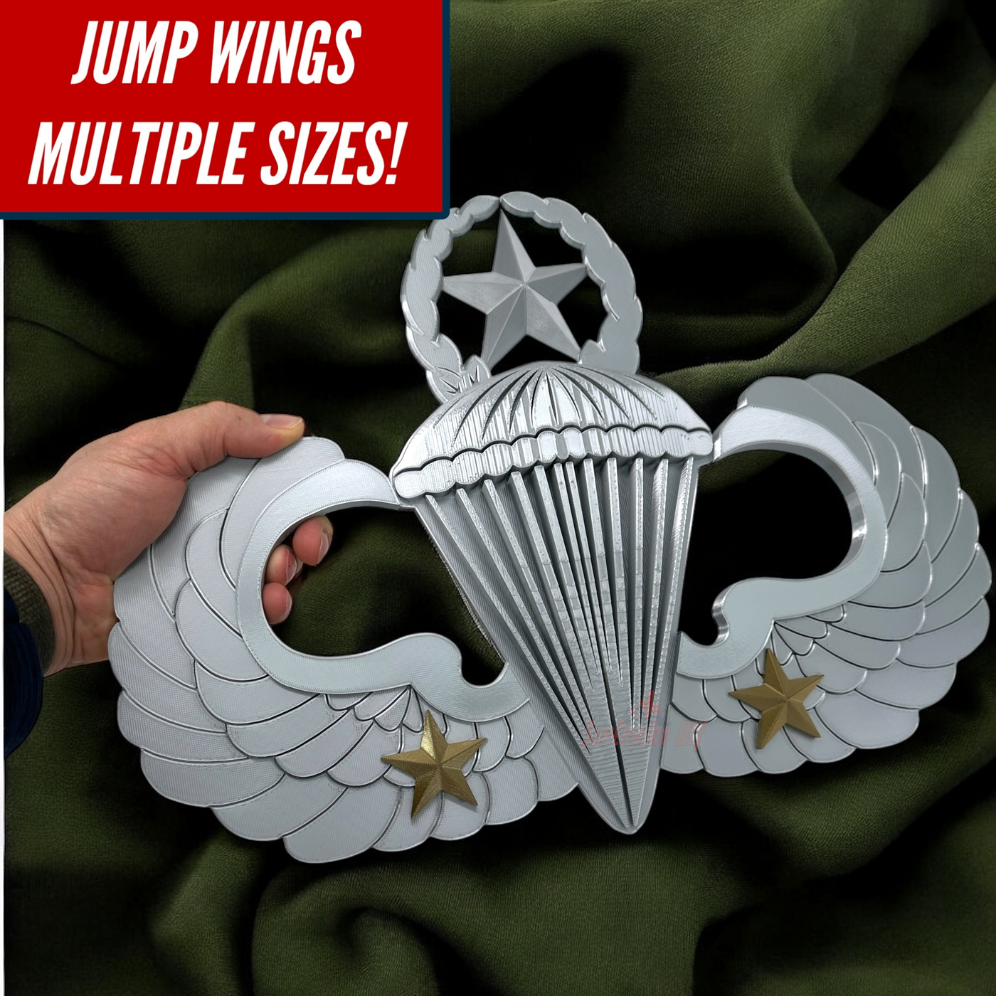 Hand holding a shiny parachutist jump wings badge against a green background, showcasing multiple sizes available.