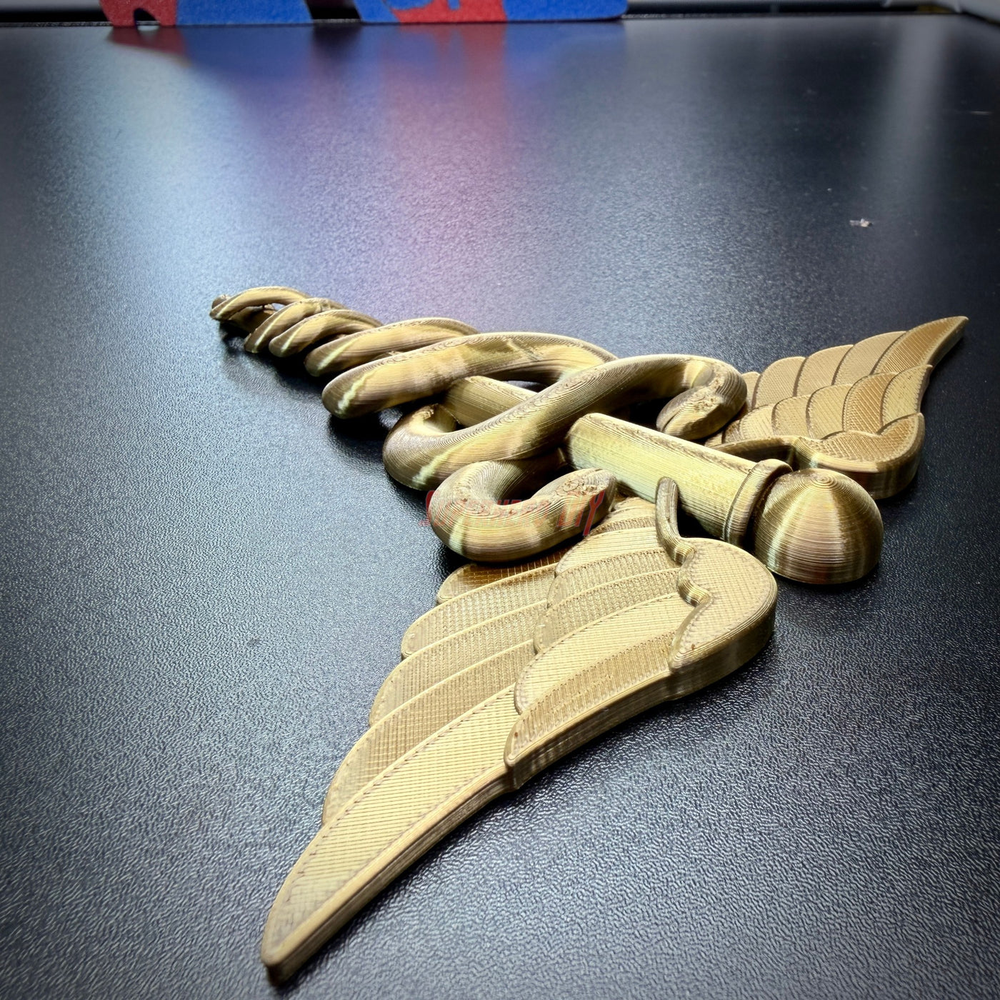 Army Medical Corps caduceus wall display in gold, featuring twin serpents and wings, detailed design for wall decor.