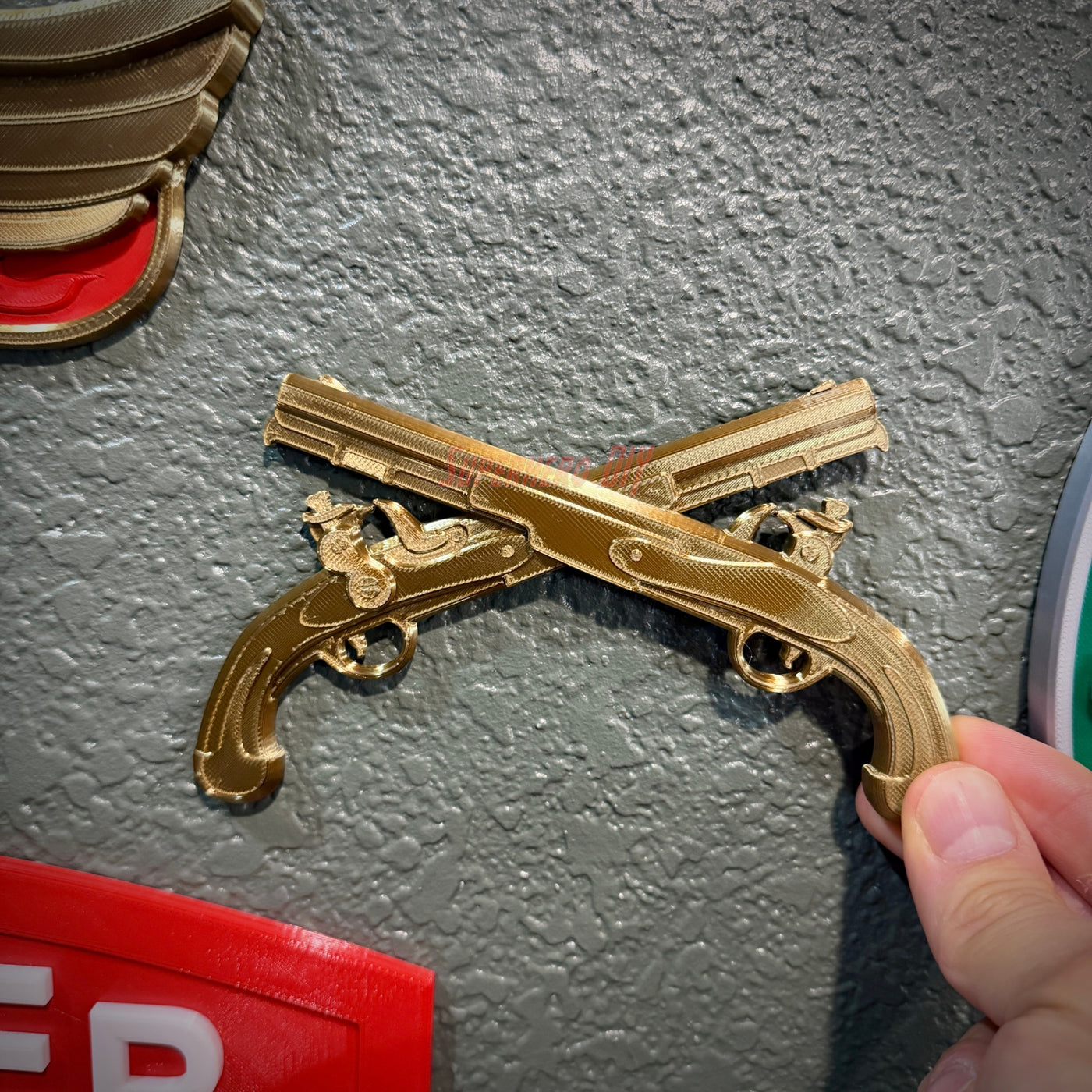 Army military police insignia displayed with crossed gold pistols on a textured wall.