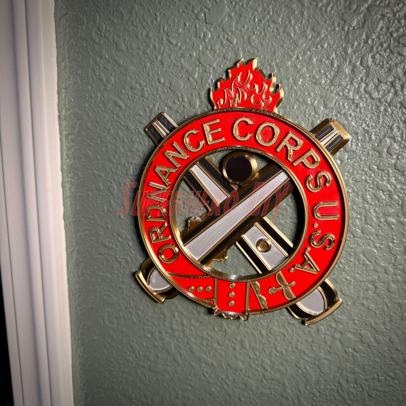 Ordnance Regimental Crest displayed on a wall, representing the Ordnance Corps, USA with red and gold colors.