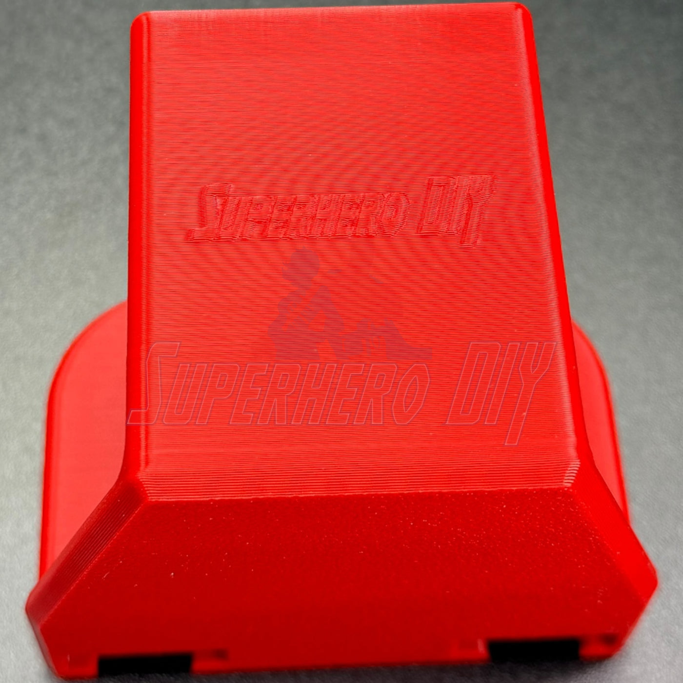 Under-desk PS5 controller mount in vibrant red, designed for charging while stored, no drilling required.