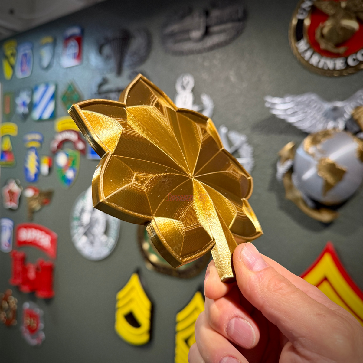 O-4 Major Navy lieutenant commander rank insignia in gold finish held against a military insignia display.