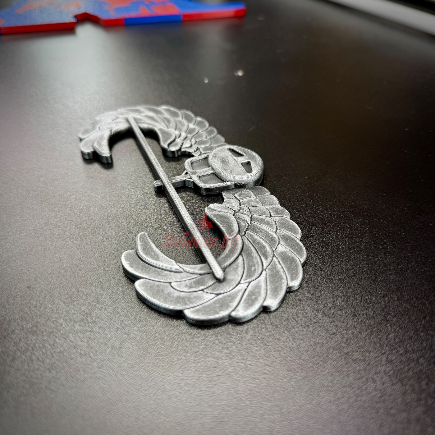 Subdued air assault badge display insignia on a black surface, showcasing hand-painted details.