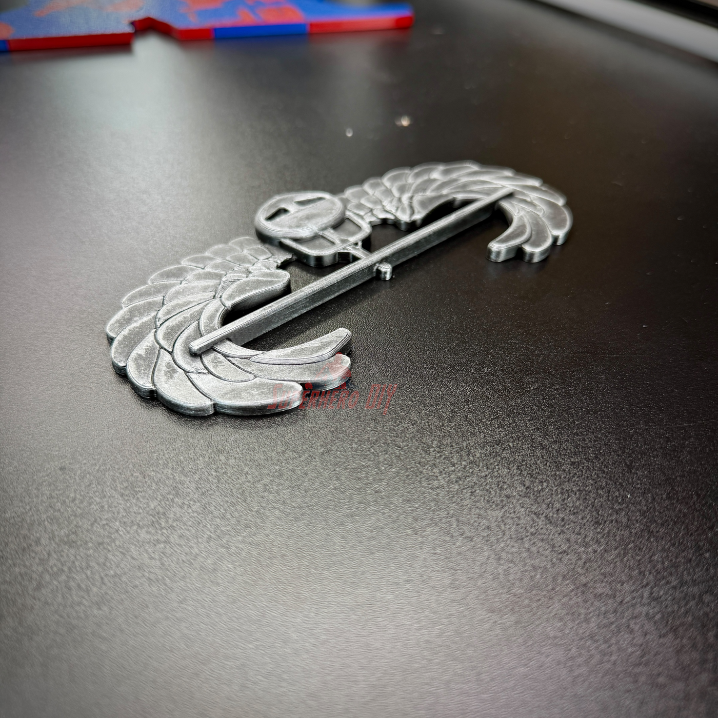 Subdued air assault badge display piece on a black surface for military showcase.