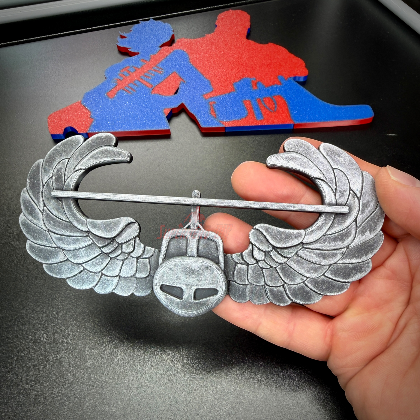 Subdued air assault badge in hand, showcasing detailed wings and military insignia.