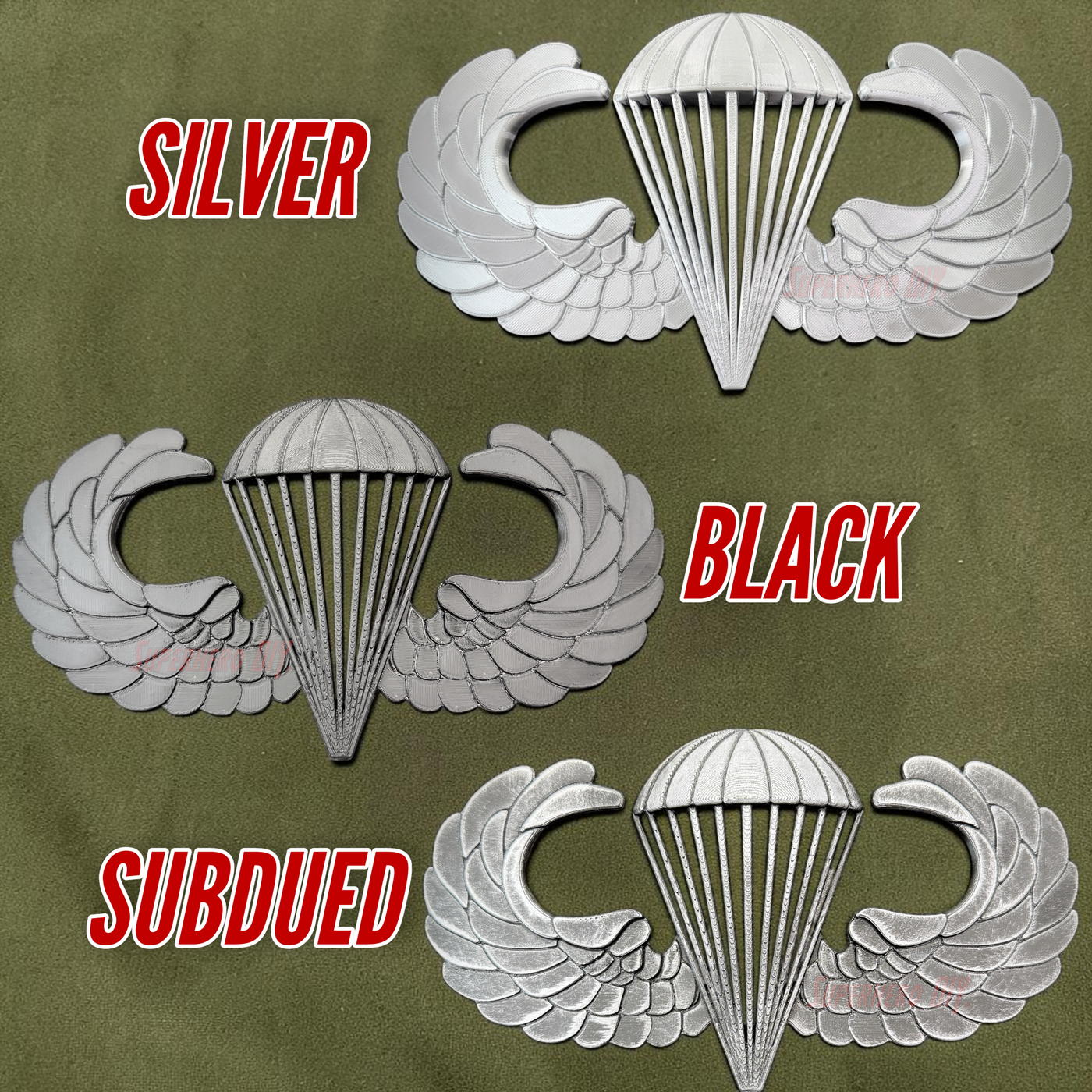 Airborne badge jump wings available in silver, black, and subdued colors displayed on a green fabric background.