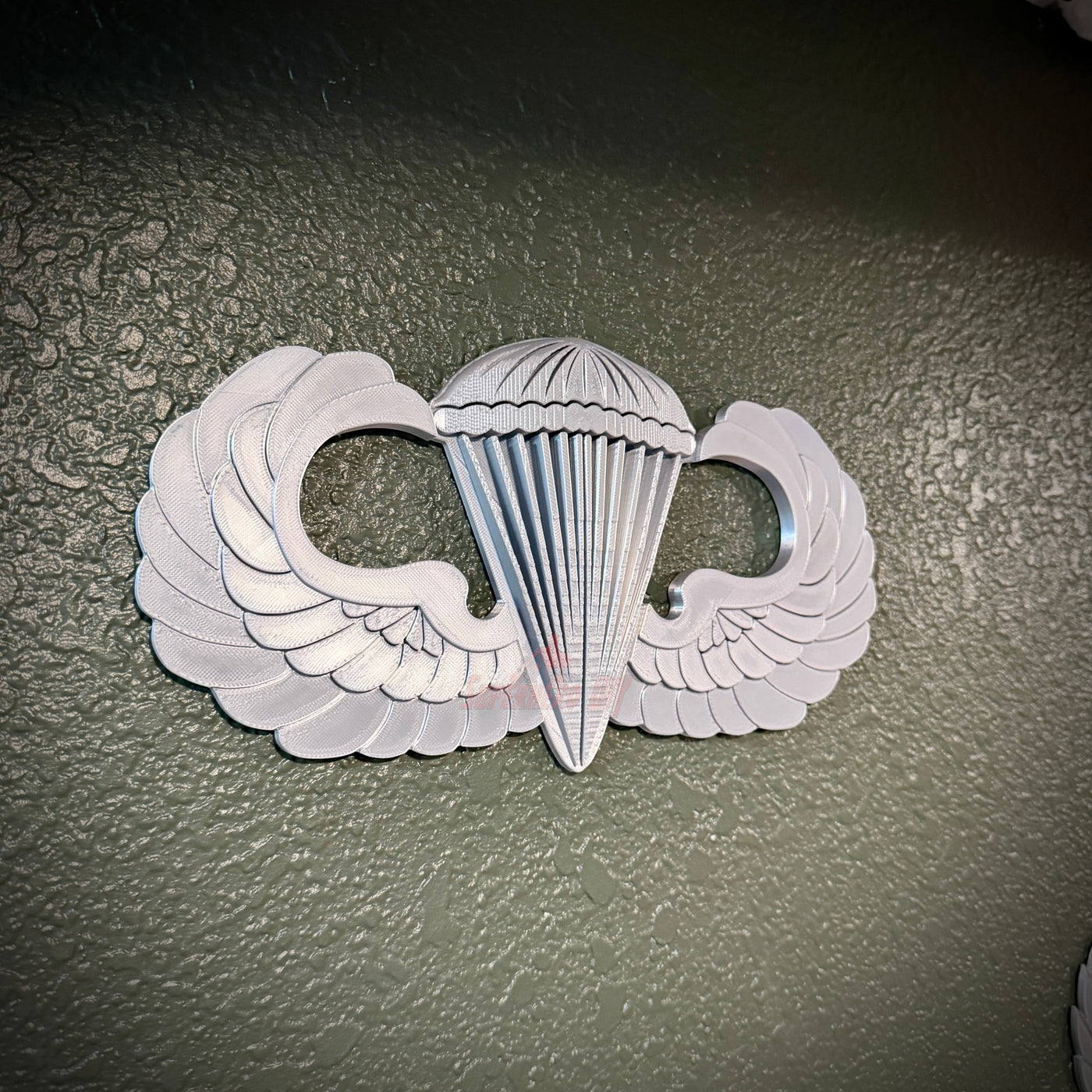 Parachutist jump wings badge with wings and parachute detail, symbolizing military airborne achievement.