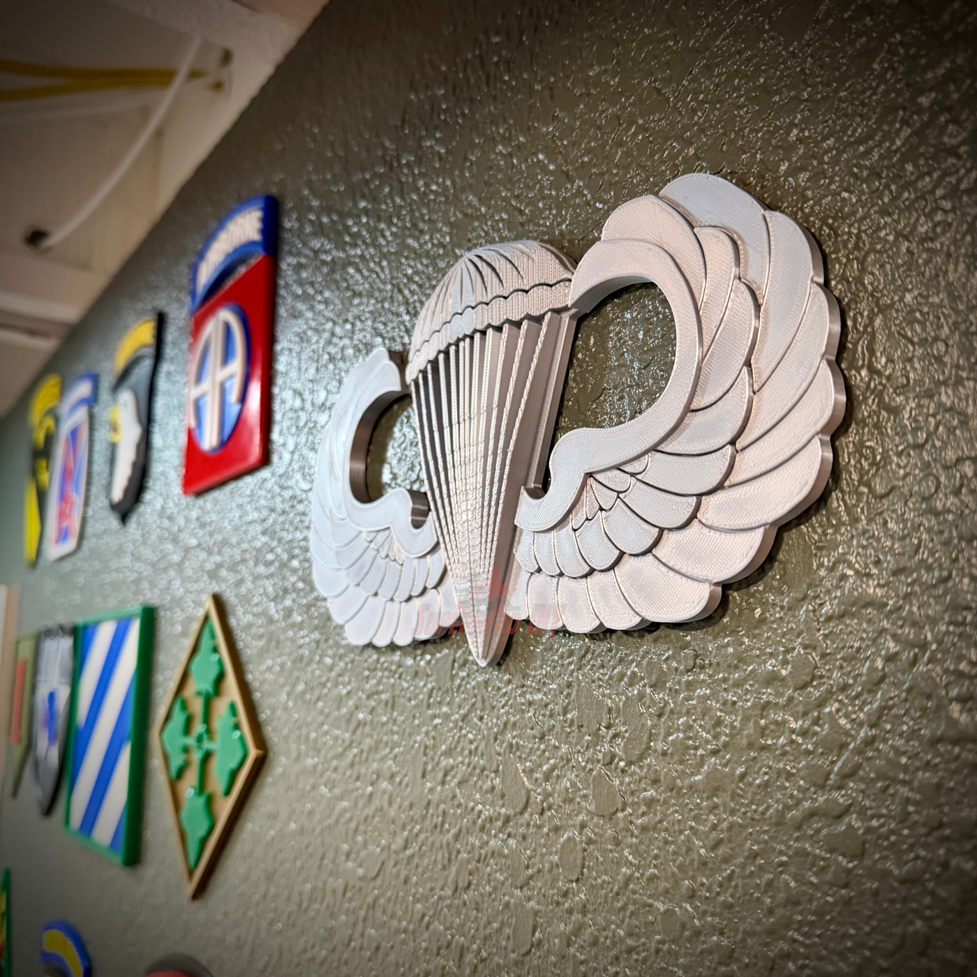 parachutist jump wings badge displayed on a wall with various military insignias behind it