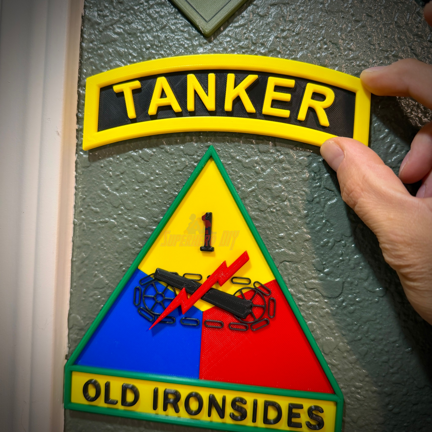 3D tanker tab with raised lettering and military insignia on a textured wall.
