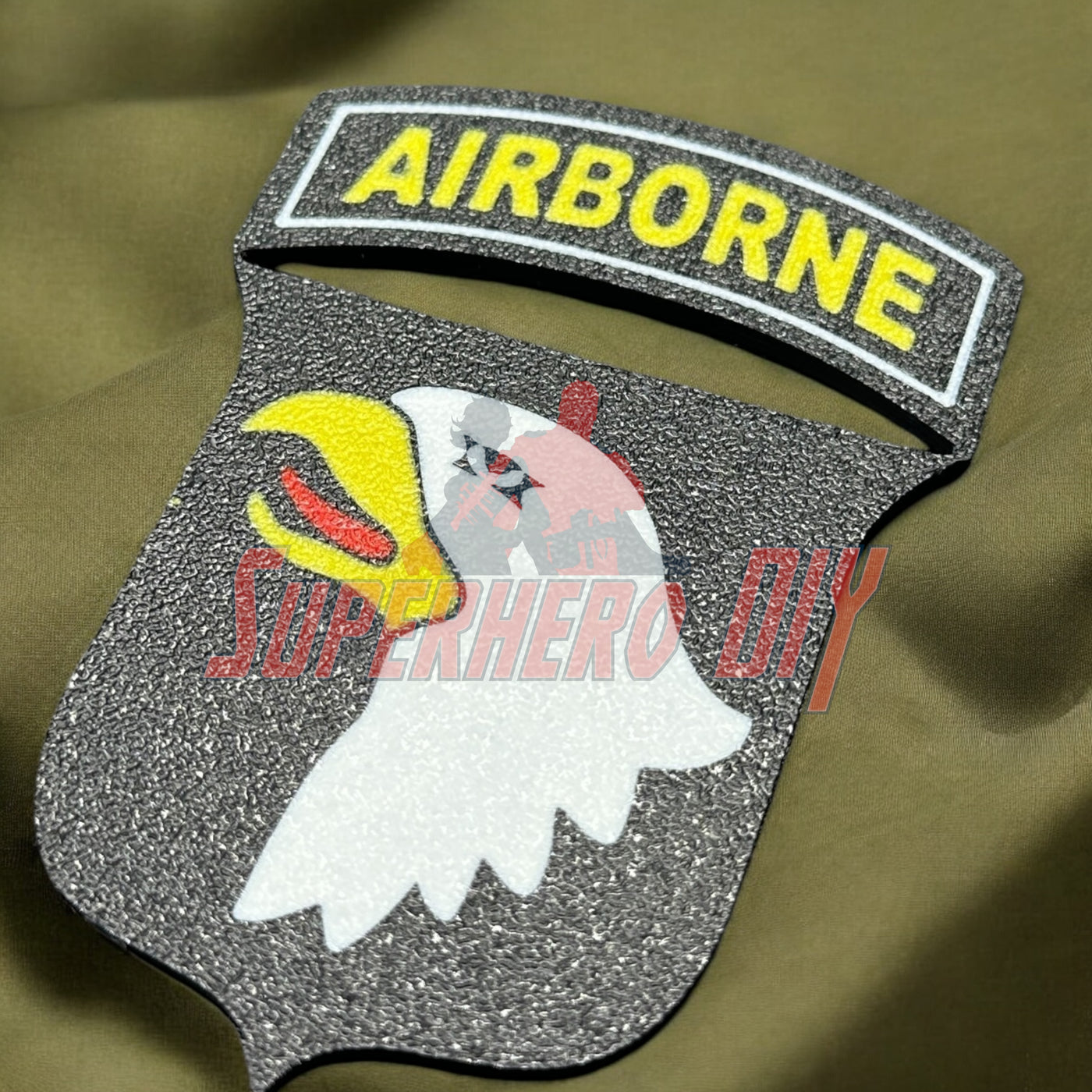 3D-printed 101st Airborne Division display insignia on olive fabric background, showcasing detailed eagle emblem.