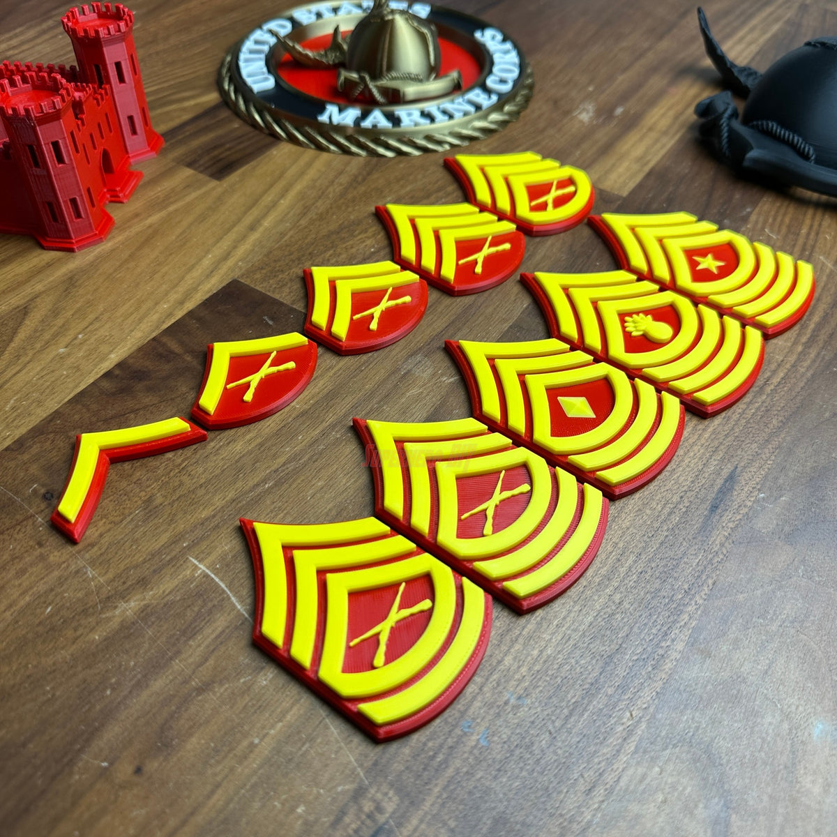 Detailed USMC enlisted rank insignias showcasing red and yellow design on a wooden surface.