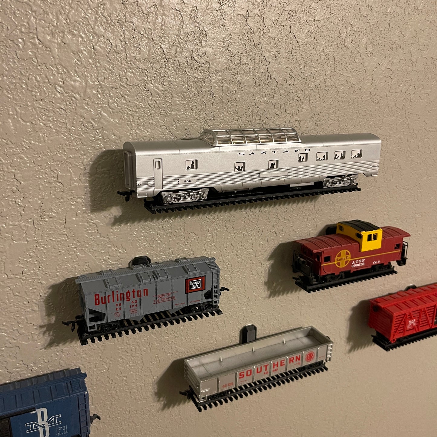 Floating HO-scale train display shelf featuring various HO scale train cars on a wall.