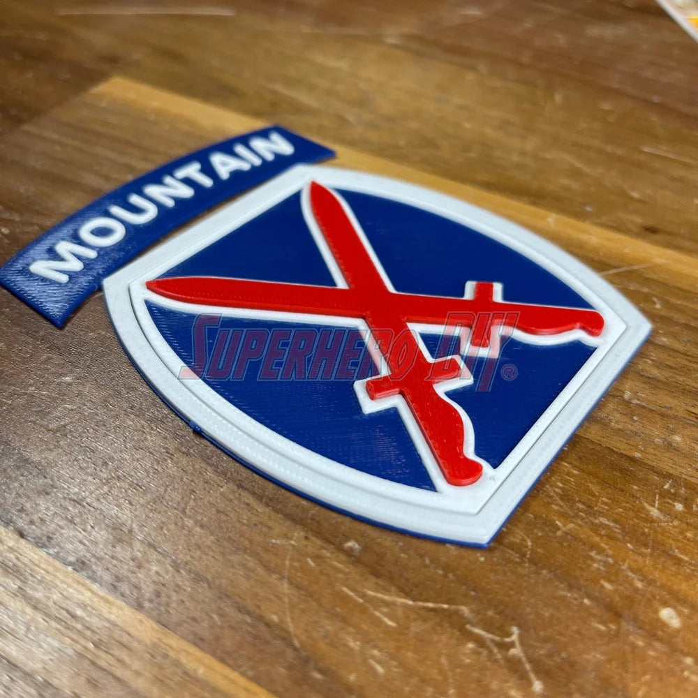 3D-printed 10th Mountain Division insignia with red sword design on wood surface