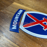 3D-printed 10th Mountain Division insignia display featuring blue, red, and white colors on a wooden surface